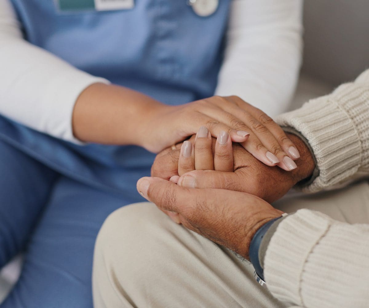 A caregiver gently holding an elderly person's hands.