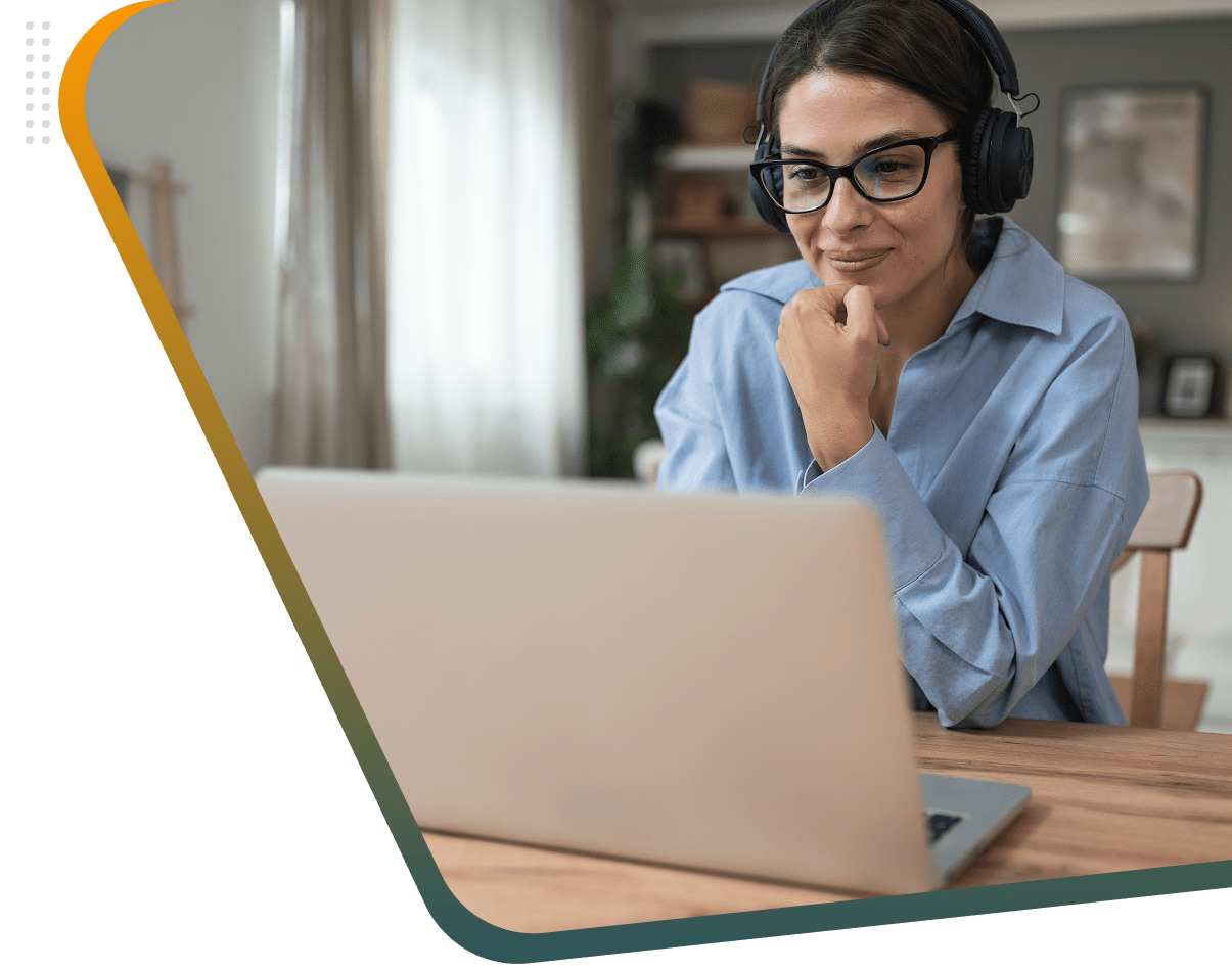 Woman wearing headphones working on a laptop at home.
